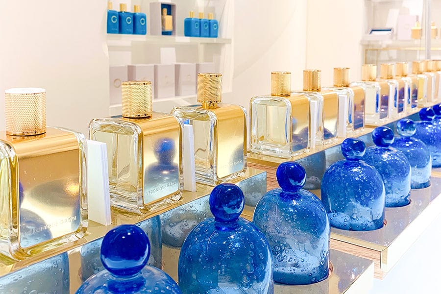 Veronique Gabai 85ml perfume bottles displayed in a line with their correspondant olfactive family presented in a blue bottle in front. 