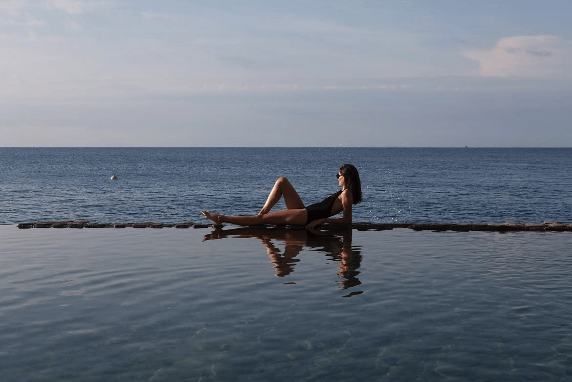 Woman at infinity pool overlooking the sea — By Personality